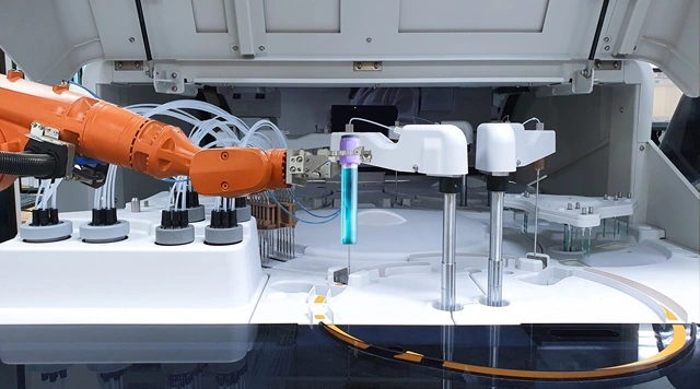 Automated robotic arm handling a sample tube in a life science laboratory analyzer.