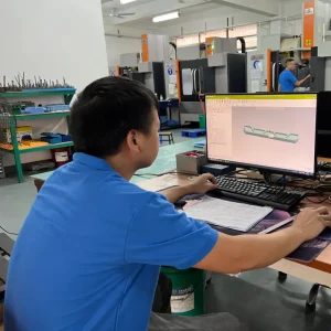 Engineer reviewing CAD model and sample parts while preparing an RFQ