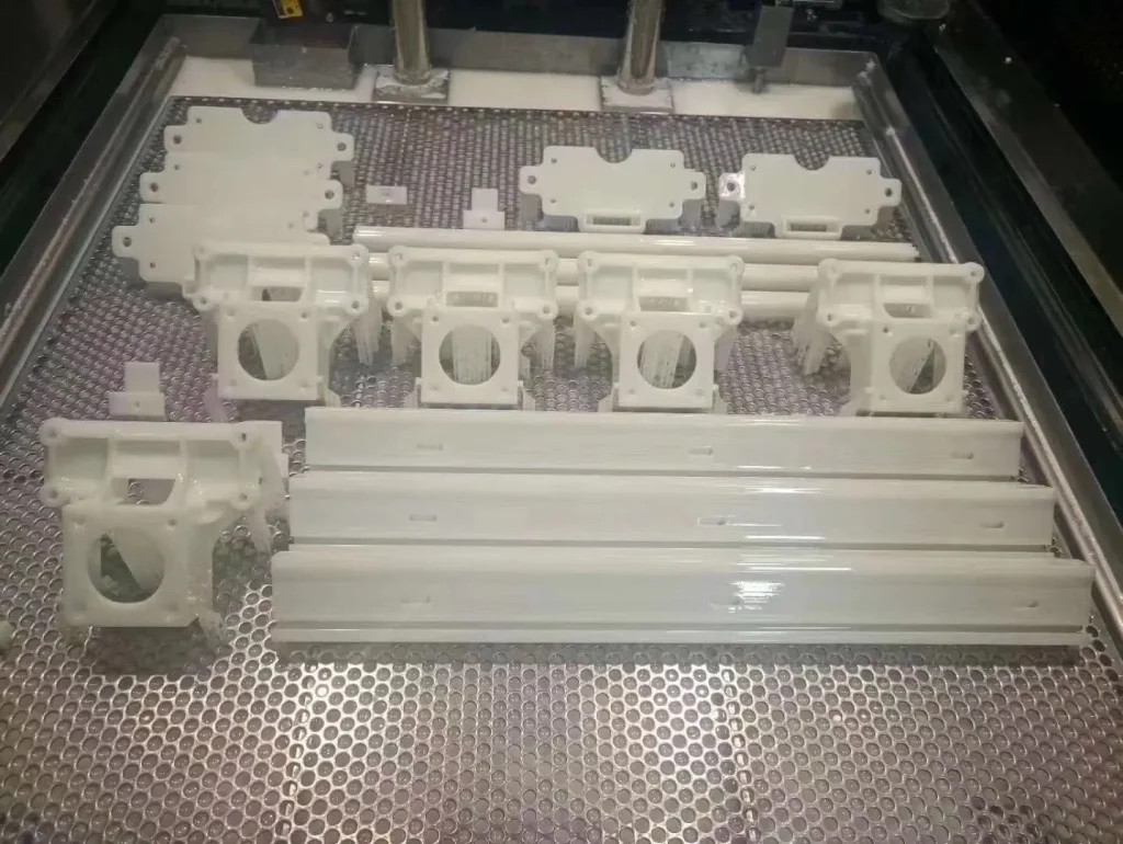 technician lifting a detailed resin part from an SLA build plate