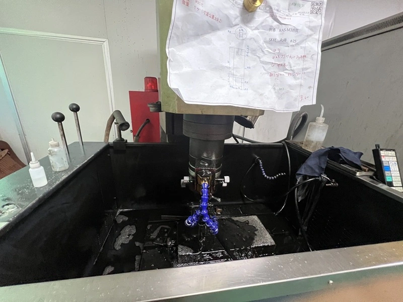 Sinker EDM setup with a shaped electrode forming detailed cavities in a metal workpiece.