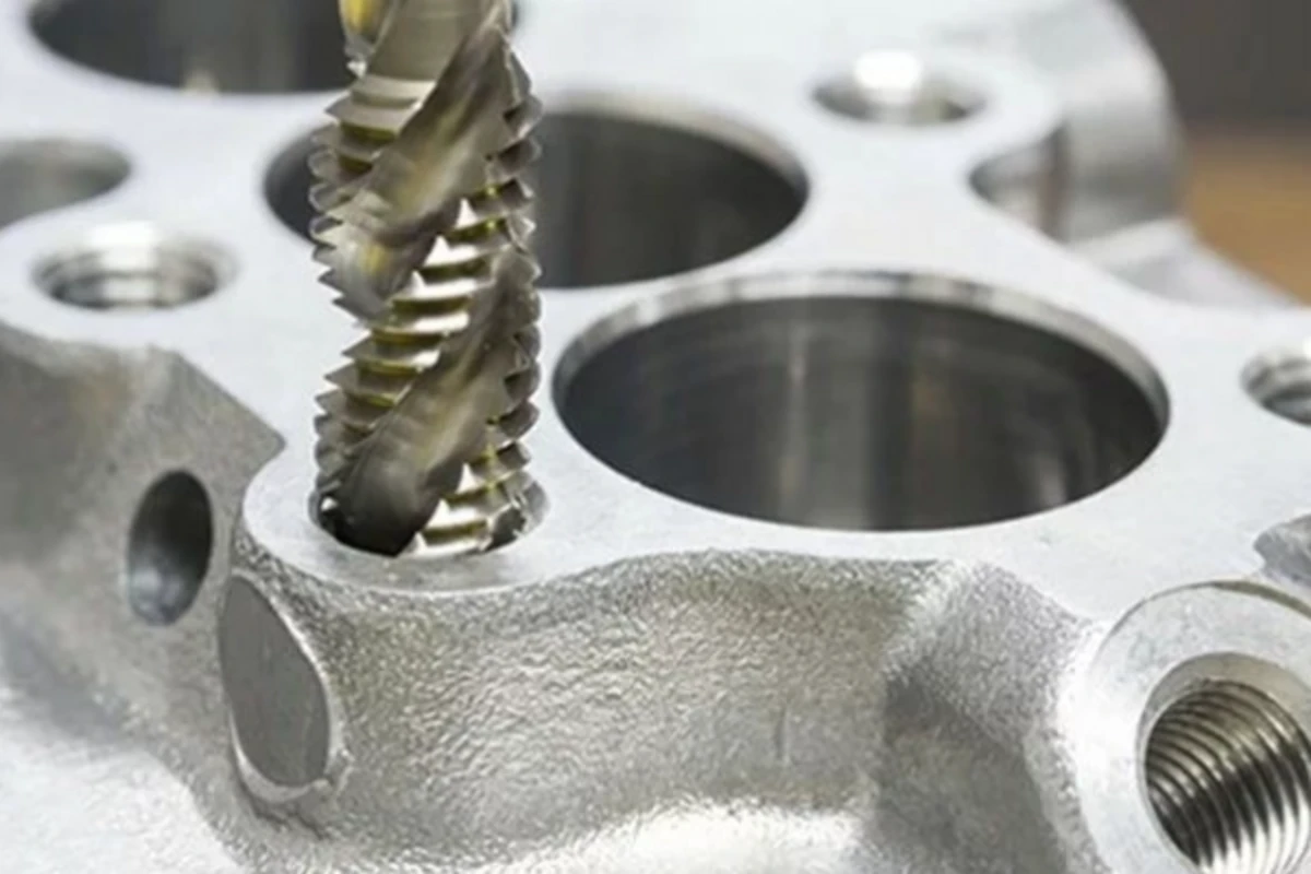 CNC machine using a tapping tool to cut internal threads in a metal part