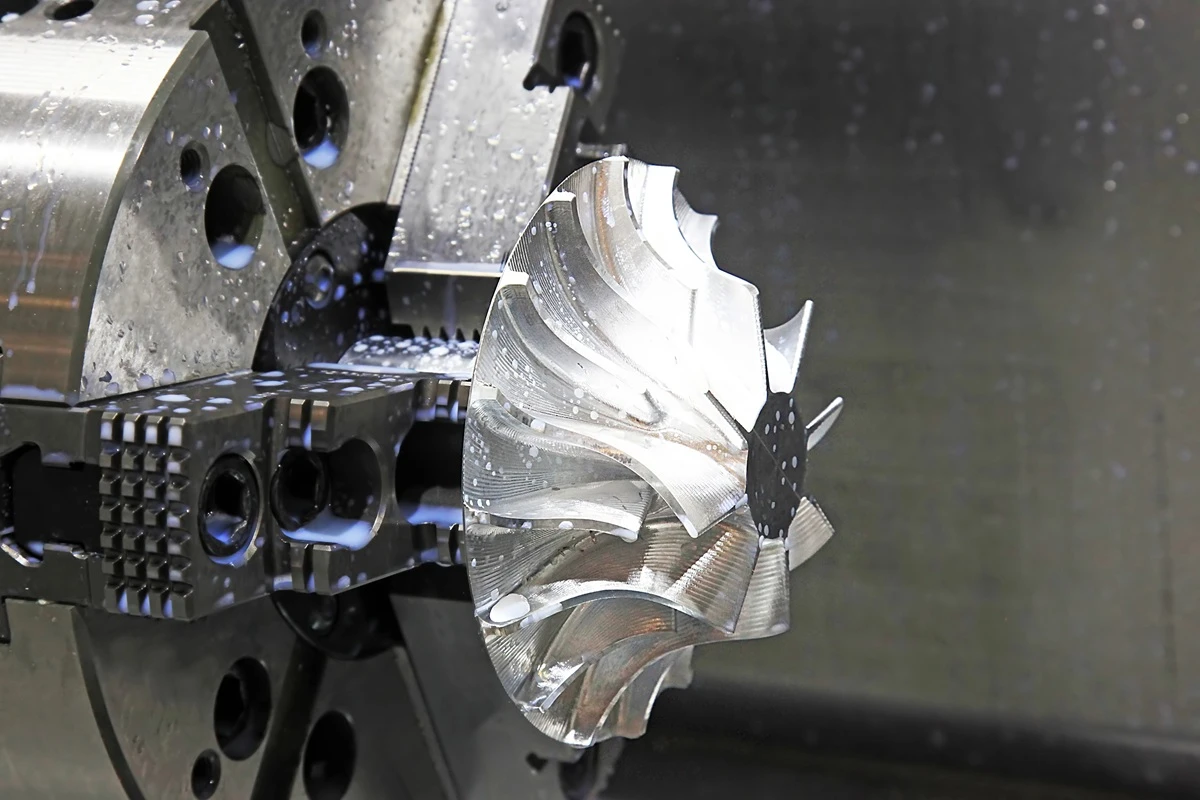Complex aerospace impeller with curved blades machined from a single block of metal using 5-axis technology.