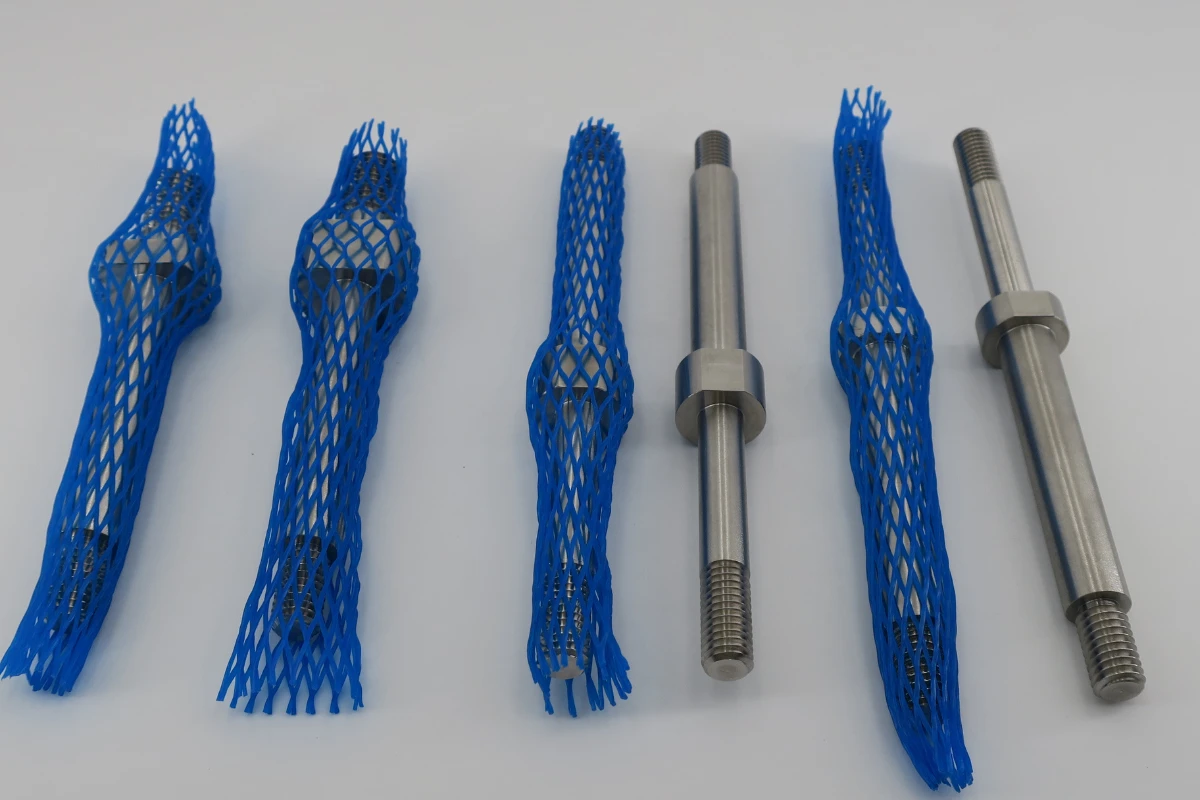 Precision turned shaft components protected with flexible mesh sleeves to reduce scratching and handling damage