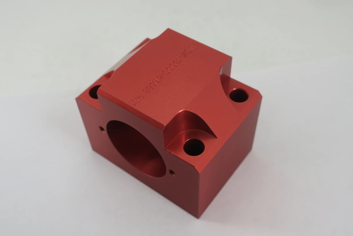 Red anodized aluminum CNC machined housing with satin finish and precision mounting holes